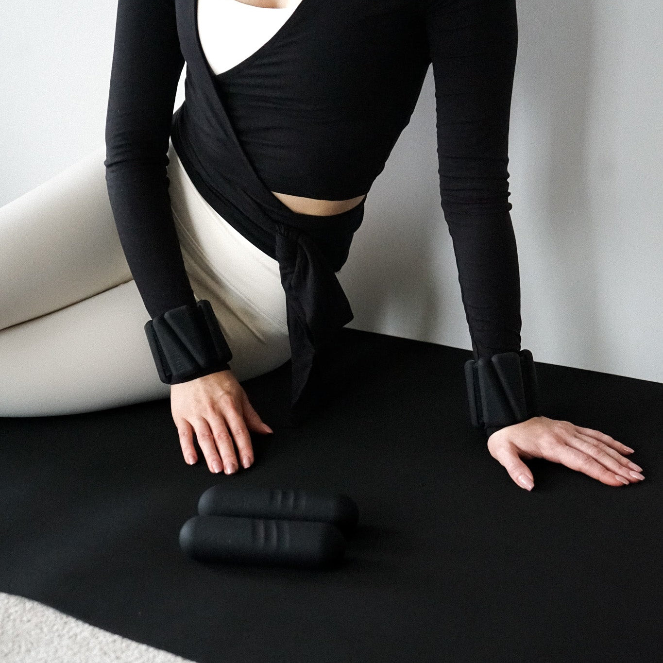 Pilates matil musta värvi käeraskusete ja 1 kg hantlitega.